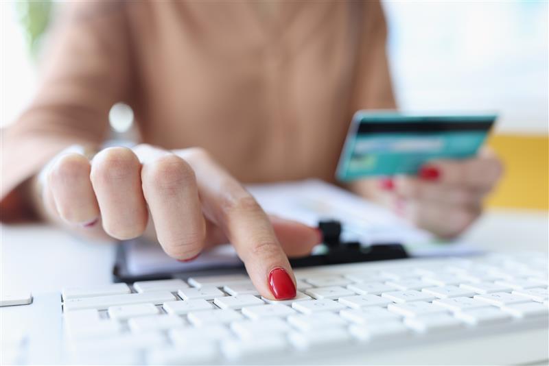 main de femme tient la carte bancaire et fonctionne sur le clavier de l ordinateur